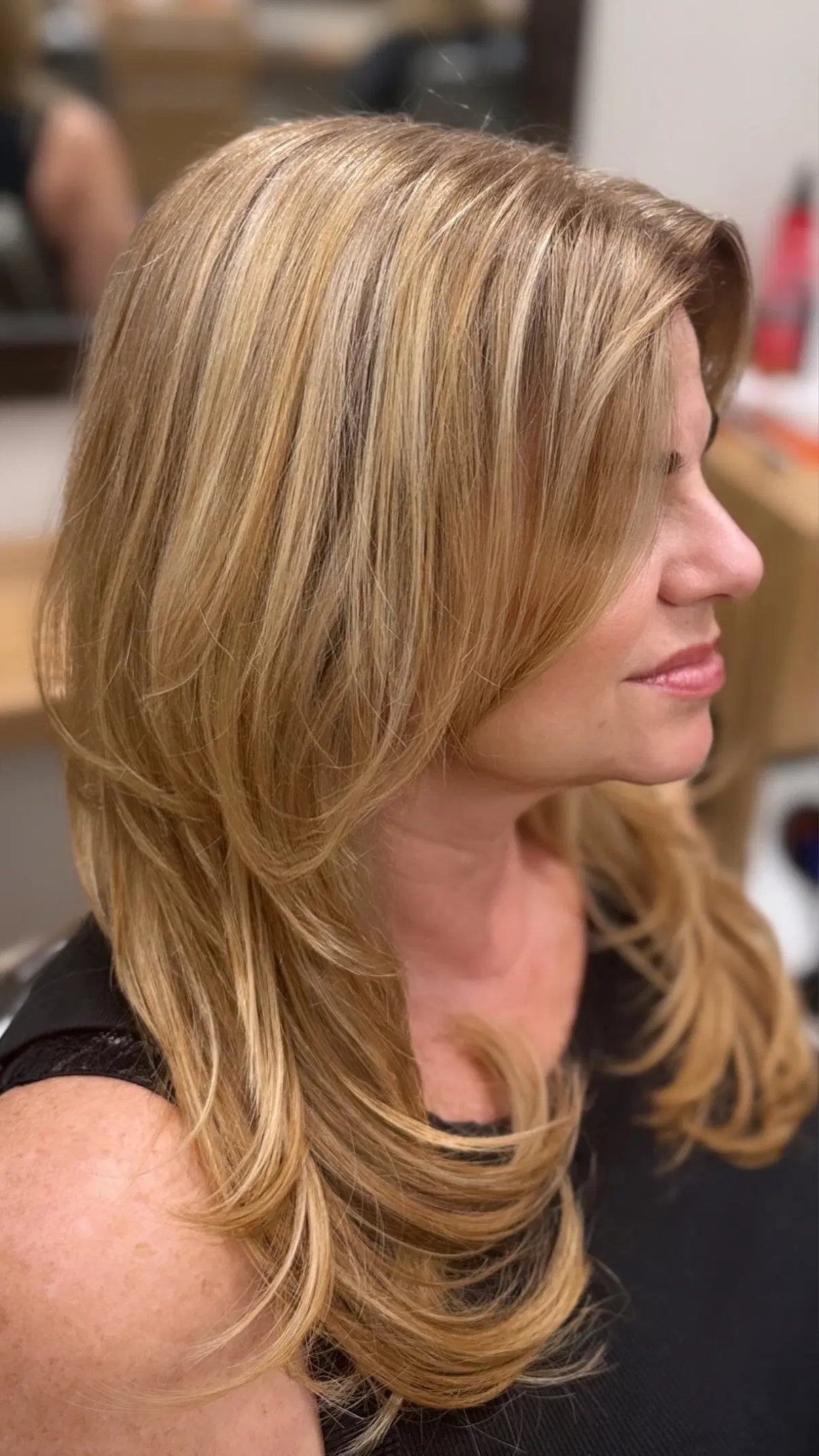 Golden blonde layers with curtain bangs, in profile
