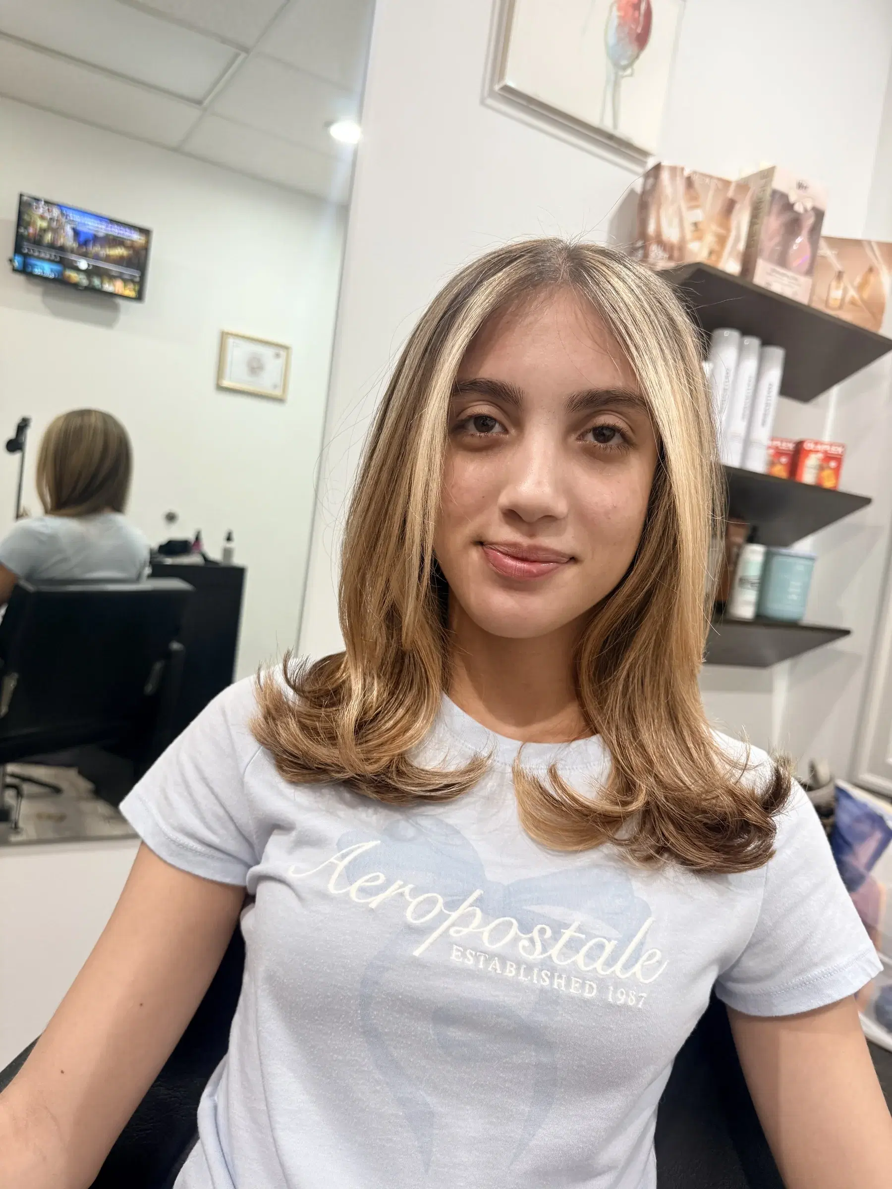 Face-framing golden blonde with a rounded blow-dry, seated in the studio